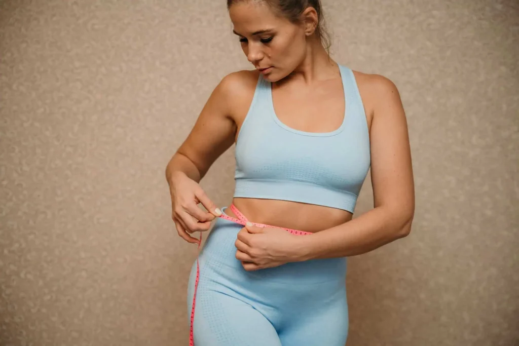 Woman in athletic wear measuring her waist, symbolizing medical weight loss in Provo, Utah