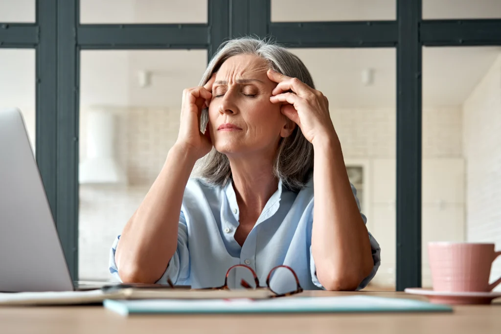 Woman experiencing perimenopause and menopause symptoms such as headaches and fatigue, treated at Optimal Health Family Practice & Medspa