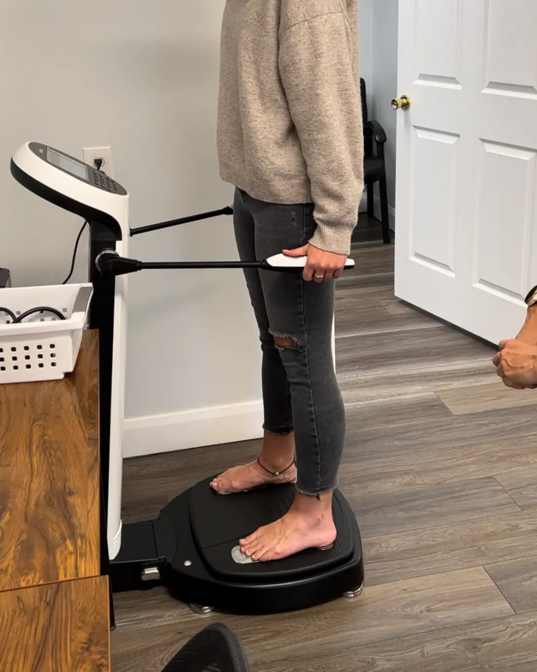 A patient standing barefoot on the InBody scanner, holding its hand grips