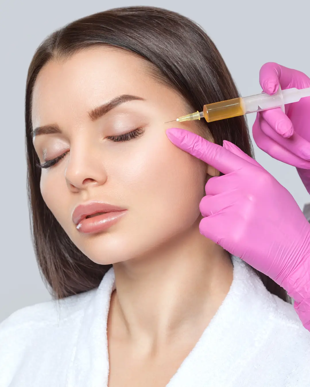 A syringe of platelet-rich plasma held near a woman's face